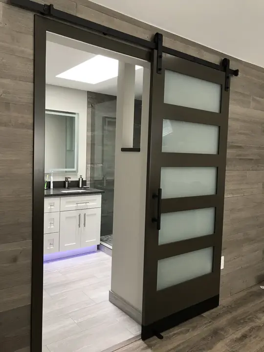 Black-framed barn door opening to a remodeled bathroom