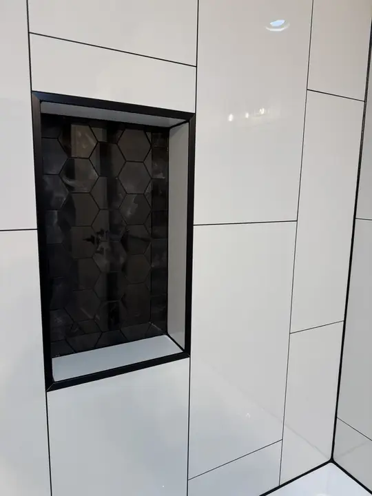 Black hex-mosaic niche framed in large white tile