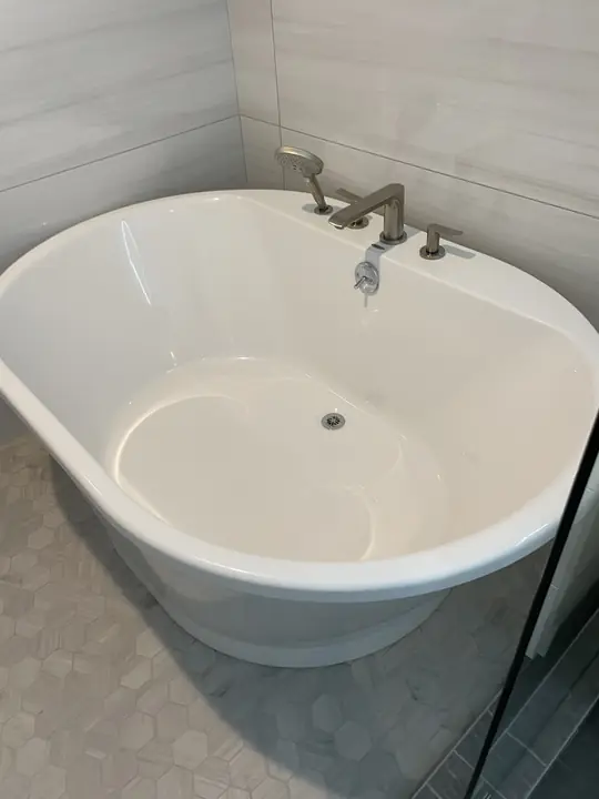 Freestanding oval soaking tub with deck-mount faucet