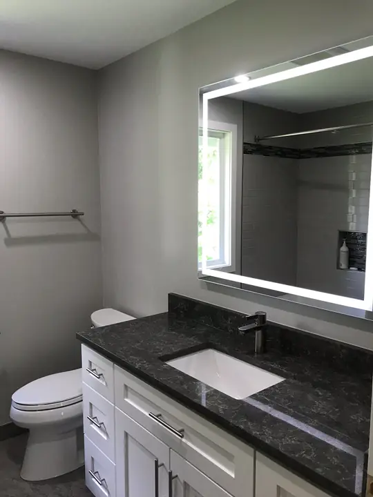 Granite-top vanity under a backlit LED mirror