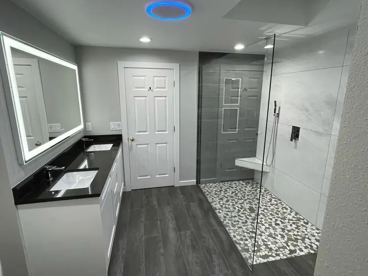 LED mirror vanity and walk-in shower with pebble floor
