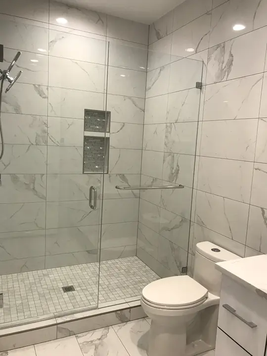 Marble glass shower with mosaic niche and floor