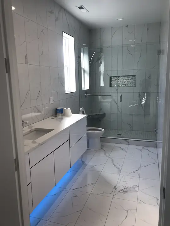 Marble bathroom with glass shower and LED under-vanity glow