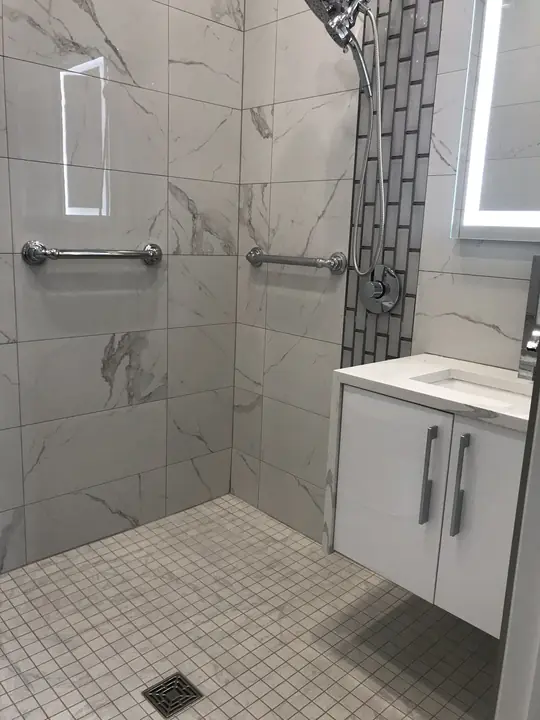 Marble walk-in shower with mosaic strip and lit niche