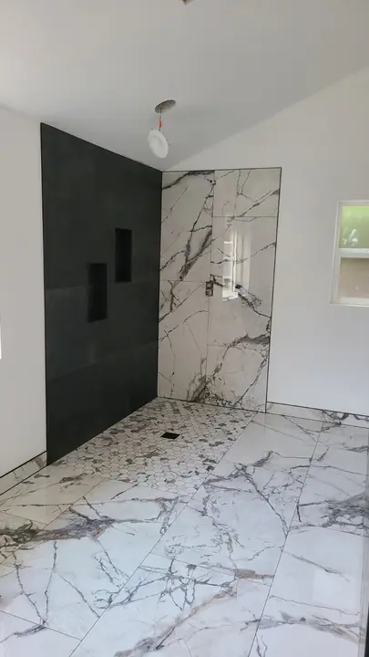 Marble wet room with matte black feature wall and niche