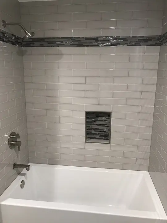 Subway-tile tub surround with mosaic niche and accent band