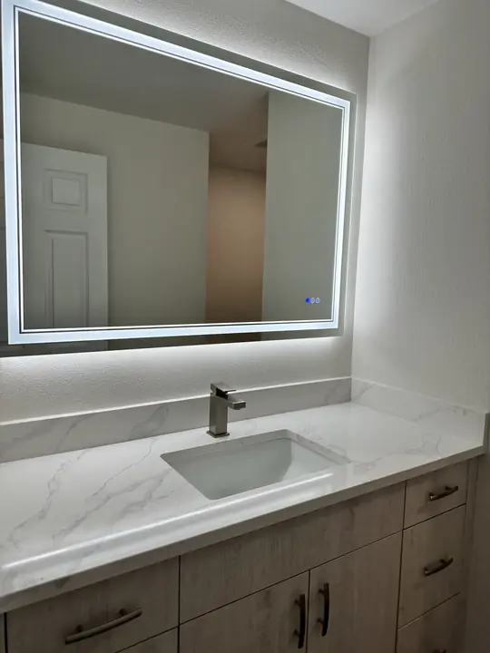 Wood-look vanity with marble top and backlit mirror