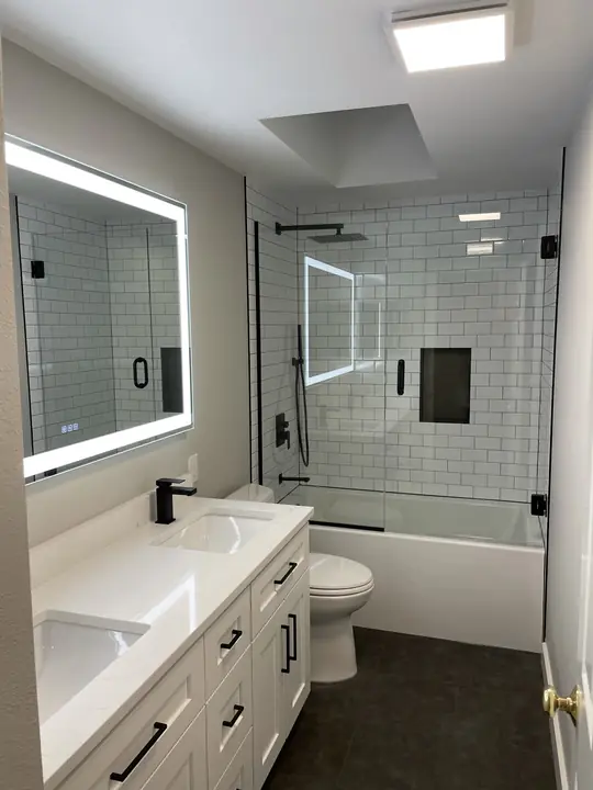 White and black bathroom with LED mirror and glass tub shower