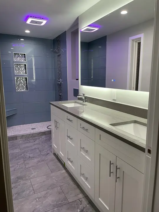 Primary suite with blue tile shower and long double vanity