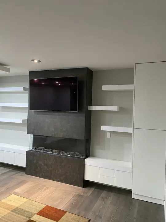 Built-in media wall with fireplace and white floating shelves