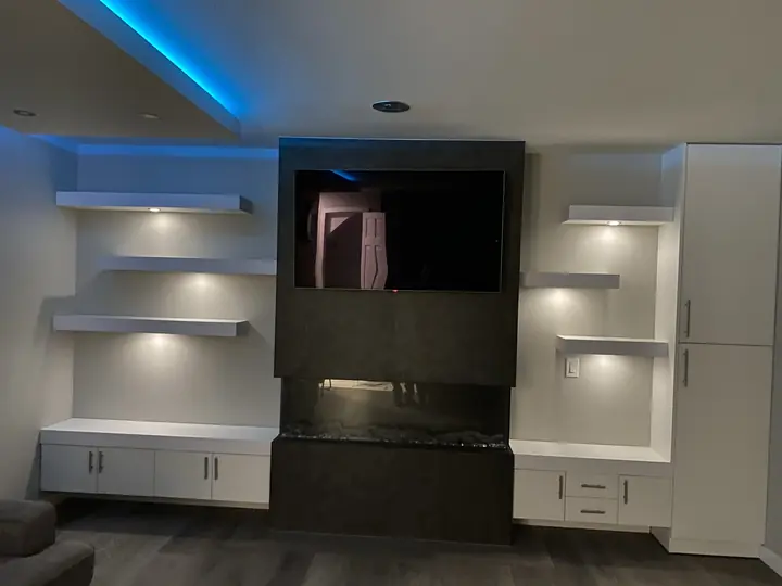 Media wall with floating shelves, cove LED and stone fireplace
