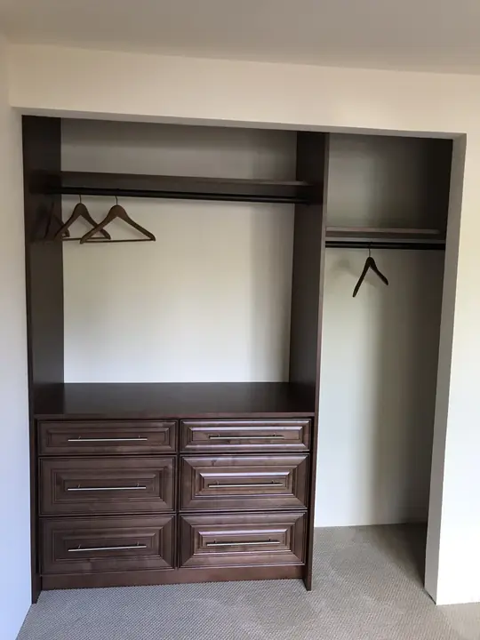 Reach-in closet with stained built-in dresser and hanging