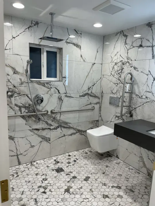 Curbless marble wet room with rain shower and pebble floor