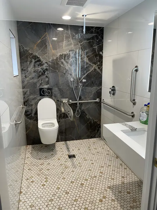 Curbless shower with stone-look slab wall and wall-hung toilet