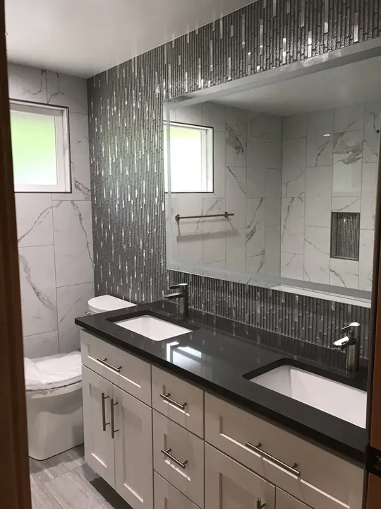 Double vanity with black quartz top and mosaic accent wall