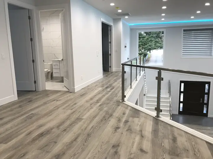 Upper landing with glass railing and wide-plank floor
