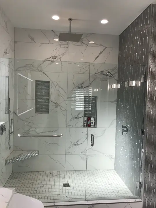 Frameless glass shower with rain head and dark mosaic feature column