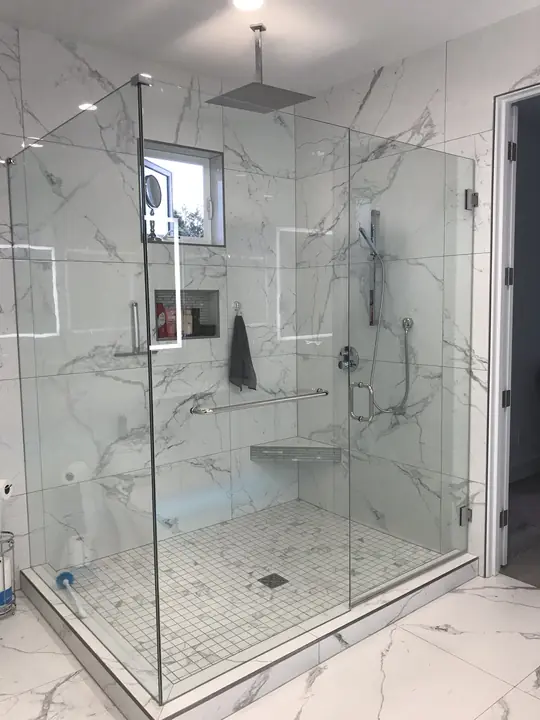 Glass-enclosed walk-in shower with corner bench and mosaic floor