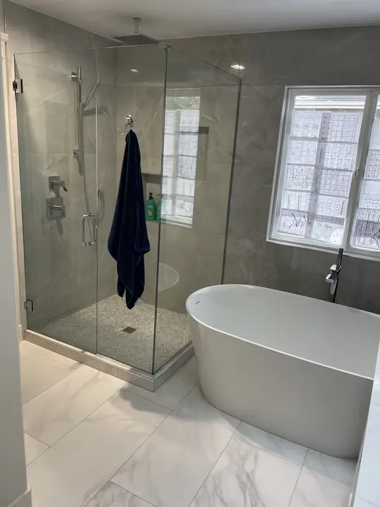 Glass shower enclosure next to a freestanding soaking tub