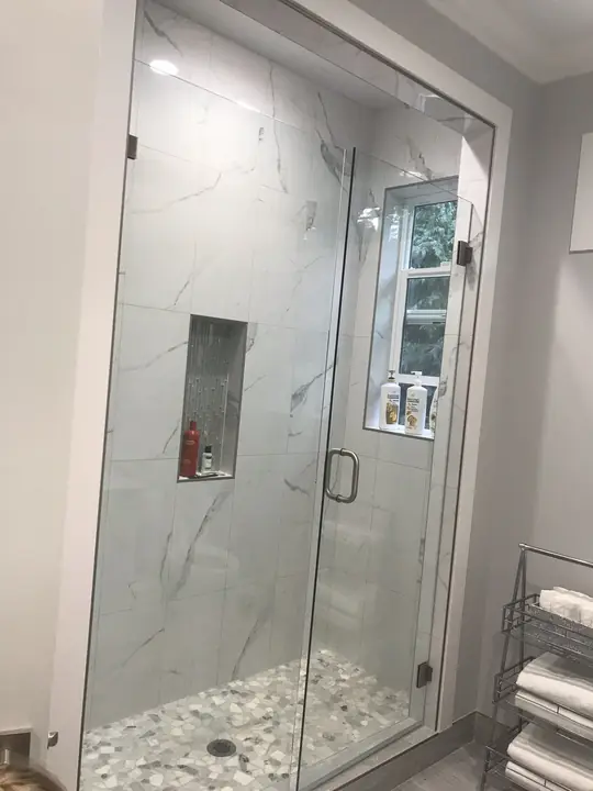 Frameless glass shower with marble walls and recessed niche