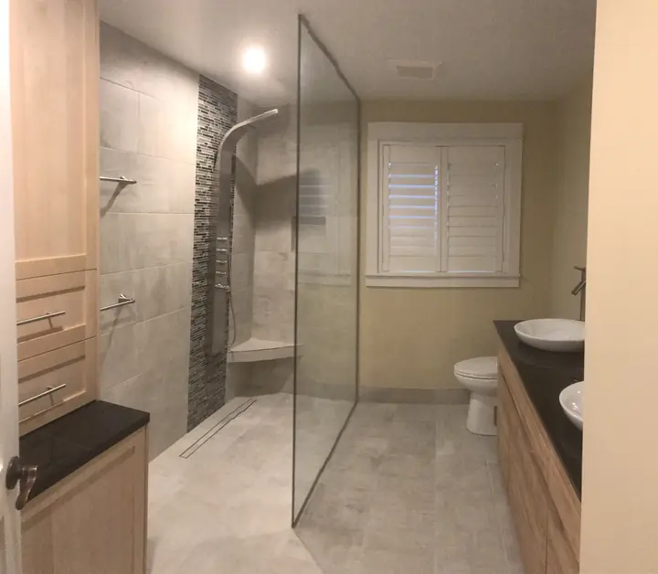 Glass-walled shower beside a dark-top vanity