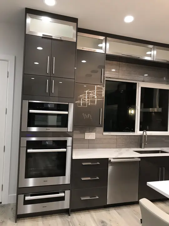 Gloss cabinetry with stacked wall ovens and quartz counters