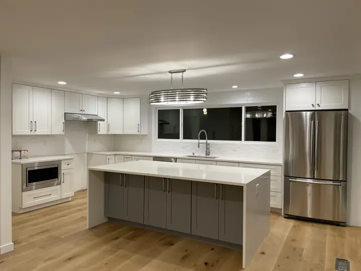 White kitchen with gray island and light oak floor