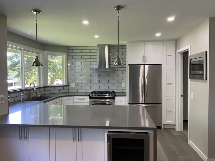 U-shaped kitchen with gray quartz counters and glass subway tile