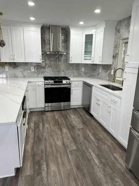 White shaker kitchen with full-height marble backsplash and range hood