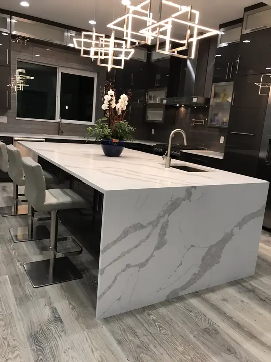 Waterfall quartz island under sculptural pendant lights