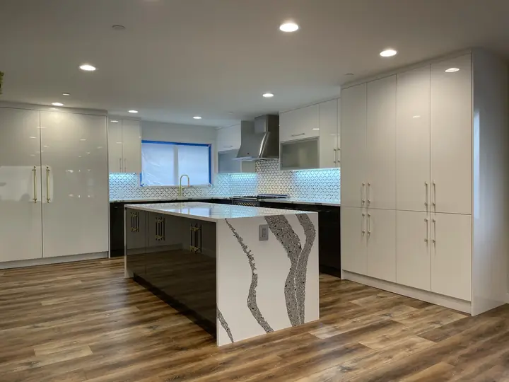 White flat-panel kitchen with a dark waterfall island