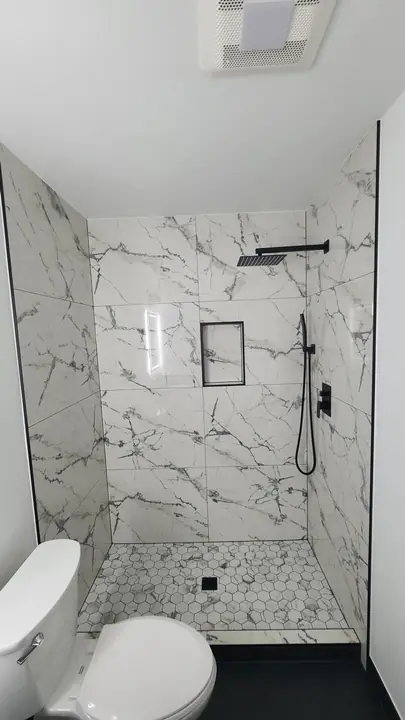 Marble shower with matte black fixtures and mosaic floor