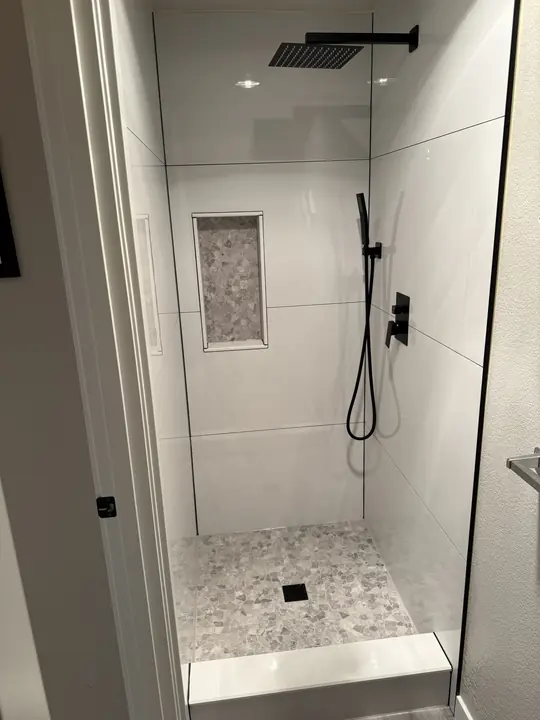 Walk-in shower with matte black fixtures and stone niche