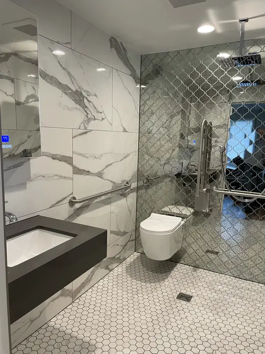 Accessible bathroom with floating stone vanity and mirrored tile wall