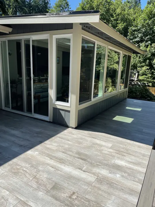 Tiled patio wrapping a glass sunroom