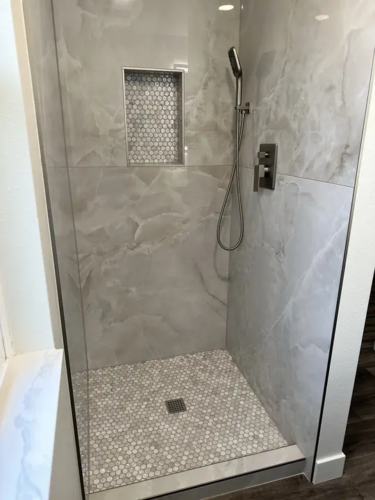 Large-format porcelain shower with hex mosaic floor and niche