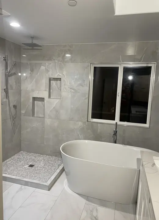 Freestanding tub in front of a walk-in shower with stacked niches