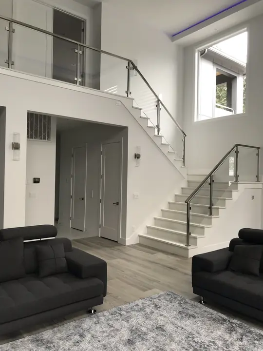 Living room with glass-railed staircase and plank flooring