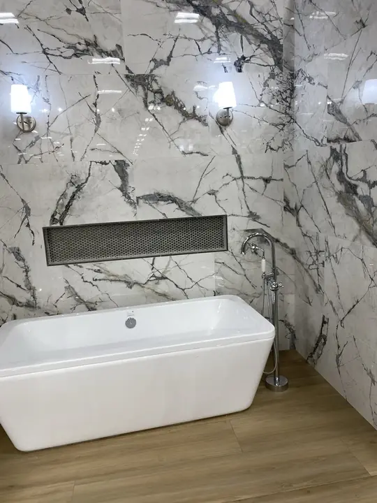 Freestanding tub against statement marble with lit ledge
