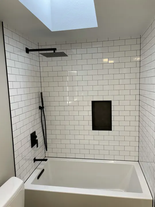 Subway-tile tub surround with matte black rain shower