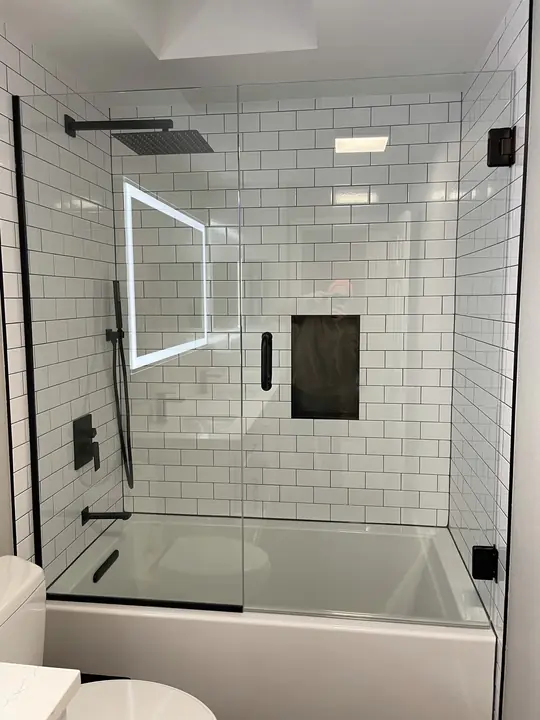 Subway-tile tub with glass panel and lit niche