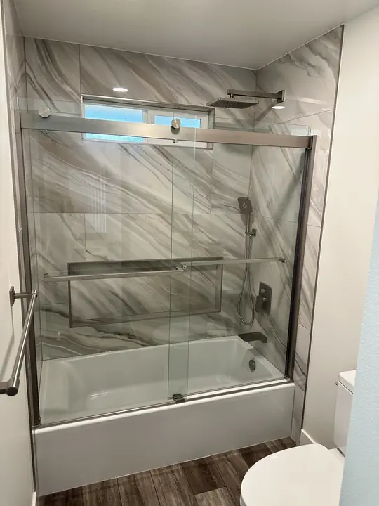 Tub with sliding glass doors and sweeping veined tile