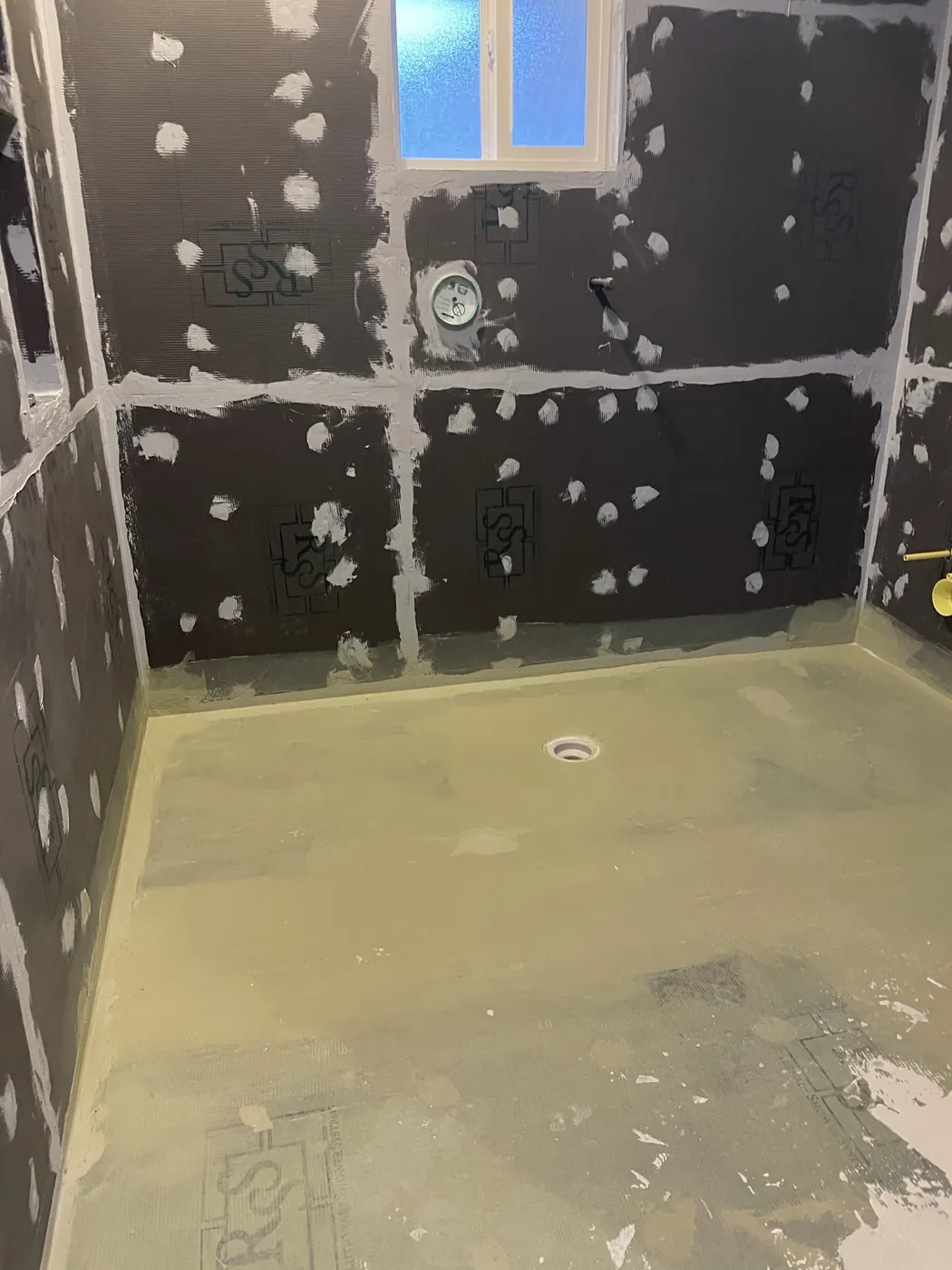 Waterproof wall boards with sealed seams over a sloped shower pan, before tile